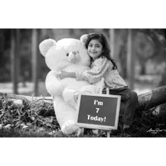 A quiet moment captured in monochrome. Brishka smiles as she hugs her large teddy bear, with the "I'm 7 Today!" sign adding context to this sweet seventh birthday photo.