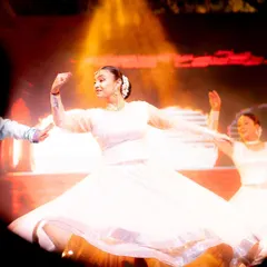 A dancer in a white dress twirls, her skirt catching the warm stage light beautifully. This is a great example of capturing motion and the flow of fabric to add energy to a still photograph.
