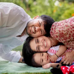 A happy pile of love! This family shares a laugh while relaxing on a blanket in the park, creating a warm and authentic family portrait.