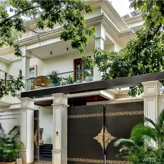 'The White House' in Bangalore features a classic, elegant exterior with subtle ornamentation. The grand gate and pillars are framed by lush greenery, creating a perfect blend of tranquility and luxury.