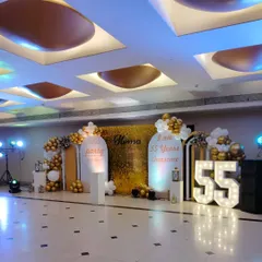 Here is a wide view of a grand 55th birthday celebration I decorated in a large venue. The setup includes a gold shimmer wall, custom arched panels with personalized messages, and large light-up '55' numbers, all tied together with white and gold balloon arrangements.