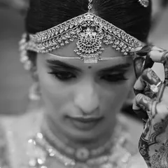 A stunning black and white portrait of the bride, her henna-adorned hand delicately touching her headpiece. This artistic shot is full of grace and emotion.
