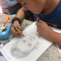 Here is Shahbaaz in action, using the grid method to ensure accurate proportions for his self portrait. This foundational technique helps young artists tackle complex subjects with confidence.