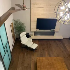 An overhead view of a transformed 70-year-old home in Delhi. We replaced solid walls with glass and opened up the ceiling to create this double-height living area, using warm wood flooring and contemporary furniture to craft a modern, light-filled sanctuary.