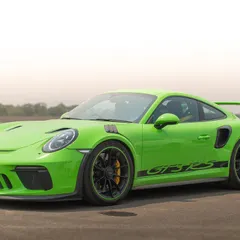 A clean, static portrait of a Porsche GT3 RS, highlighting its aggressive design and vibrant color against the simple backdrop of the runway.
