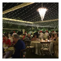 Guests enjoying a multi-course meal at a beautifully appointed round table, complete with elegant chandeliers and ambient lighting, showcasing our expertise in creating intimate yet grand dining settings.