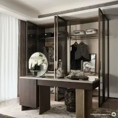 This image displays a custom walk-in closet and vanity area integrated within the master suite. The glass-paneled wardrobes and dedicated dressing table provide a functional and elegant personal grooming space.