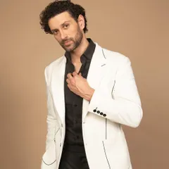 A crisp white blazer with fine black piping detail. Paired with a black shirt, this creates a sharp, high-contrast look that is both modern and timeless.