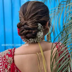 This textured bridal bun features interwoven sections for added dimension and volume. I accented the look with baby's breath and a single red carnation, creating a beautiful contrast against the bride's red lehenga.