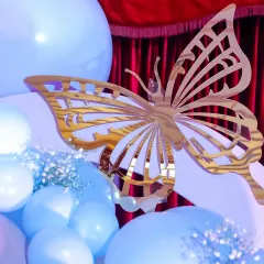 A beautiful detail shot of a golden butterfly accent on a blue balloon, part of the enchanting decor for a fairy-themed first birthday.