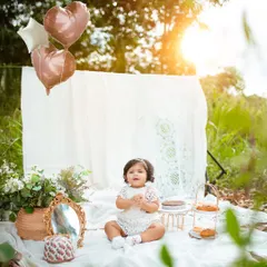 Heart-shaped balloons add a touch of celebration to this dreamy outdoor first birthday session. It's all in the little details.