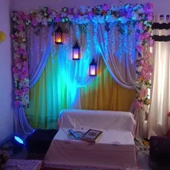 An intimate indoor ceremony backdrop created with layers of drapes and floral borders. Hanging lanterns and colored uplighting are used to create a warm and magical ambiance, perfect for an evening sangeet or nikah ceremony.