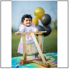 A fun and candid moment from an outdoor first birthday photoshoot. I use props like this wooden walker and balloons to encourage natural play and capture genuine smiles.