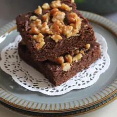 A stack of fudgy walnut brownies. We teach you the secrets to achieving that perfect chewy texture and crinkle top, without using eggs.
