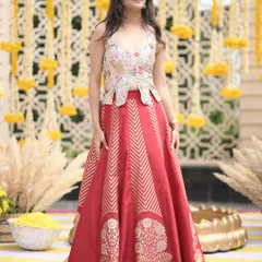 A client looking radiant at her Sagan ceremony in a custom red brocade lehenga paired with a modern, embroidered peplum-style top.