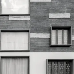 Symmetry and proportion are explored through minimalist geometry and a mix of textured and smooth facade finishes.