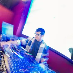 An artistic long-exposure shot capturing the motion and speed of mixing tracks. The lights and movement represent the flow of the music.