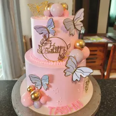 A lovely pink two-tier butterfly cake with gold and lavender butterflies, perfect for an elegant birthday.