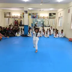 A single student takes the floor, demonstrating her Poomsae with focus and precision in front of her peers and the examiners.