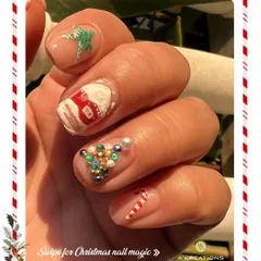 Intricate Christmas nail art featuring a variety of detailed, festive 3D embellishments, including a house, candy cane, and a jeweled Christmas tree.