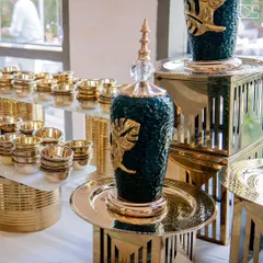 A close-up of the exquisite details in my buffet decor. This decorative green and gold urn, paired with hammered gold platters, showcases the premium quality of my serveware that elevates any event's ambiance.