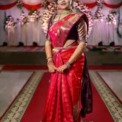 A full-length portrait of the bride in her stunning red silk saree, standing on the red carpet aisle. This shot captures the complete bridal look in all its glory.