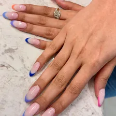 A full view of the multi-color French tip extensions. Each nail has a different pop of color, from blue and orange to pink, creating a playful yet cohesive look.