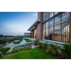 An outdoor patio and terraced garden at the Nandi Hills home. This hardscape design provides a functional space for dining and relaxation, stepping down into a manicured lawn that overlooks the valley, blending architecture with landscape.
