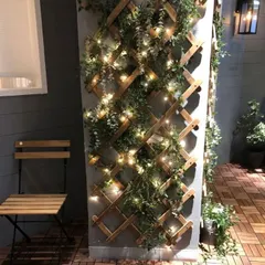 A simple wooden trellis can completely transform a plain pillar or wall. Here, I've used an expandable trellis intertwined with faux ivy and fairy lights to create a charming and whimsical green feature.