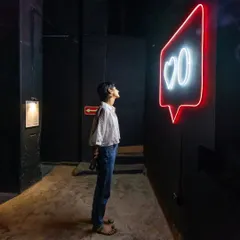 The glowing neon sign of my 'Surfing' installation creates a striking silhouette of a visitor. The piece is designed to be interactive and highly photographic, exploring themes of identity in the digital age.