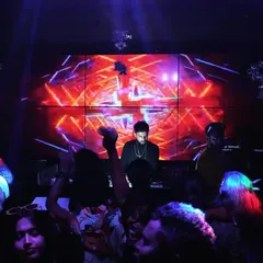 At the heart of my setup is the visual experience. Here I am at the console, surrounded by the crowd, with a massive LED wall displaying custom VJ graphics that sync perfectly with the EDM and bass house tracks.