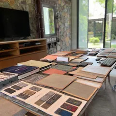 Material selection is a foundational step in our design process. Here, a wide array of material samples are laid out in our studio for review. We treat this as a thoughtful conversation, assessing how each texture, color, and finish will shape the energy of a space.