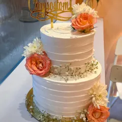 A beautiful two-tier Communion cake for Chrysostom. The simple ridged buttercream texture is elevated with delicate arrangements of fresh peach roses, white chrysanthemums, and baby's breath.