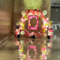A Boss Baby theme for a baby girl's birthday party. This setup features a circular balloon arch in pink, white, and gold, with character cutouts and a personalized photo frame prop for guests.