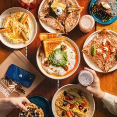 This styled flatlay for Stand By Coffee demonstrates my approach to cafe lifestyle photography. By arranging a variety of dishes, drinks, and hands interacting with the food, I create a scene that feels communal, delicious, and highly shareable.