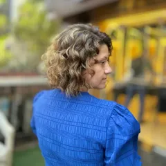 A side profile of a curly bob with bold color. This look is all about texture and dimension, with the highlights enhancing the natural curl pattern.