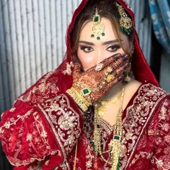 A classic pose for a classic Nikkah bride. This shot highlights the intricate henna and the dramatic eye makeup with bold liner and lashes. The combination of the red and green in her outfit and jewelry is a timeless choice.