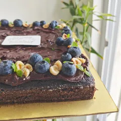 A close-up showing the texture of the sugar-free dark chocolate ganache, topped with crunchy hazelnuts and fresh blueberries.