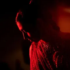 Using creative lighting to create a dramatic and artistic bridal portrait. The deep red light adds a moody and romantic feel, highlighting the bride's silhouette in a unique way.