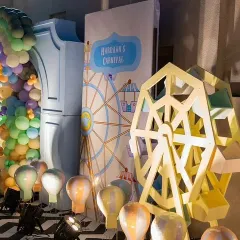 A close-up of the carnival theme decor, showing a detailed Ferris wheel prop and hot air balloon lights, perfect for a whimsical celebration.