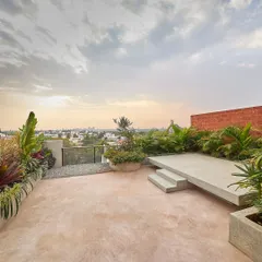 The rooftop terrace of the Magnolia Residence is a private oasis above the city. It features pigmented cement flooring, lush planters, and a raised deck for enjoying the panoramic views.