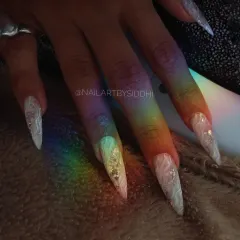 A beautiful shot of the stiletto nails under a rainbow light, highlighting the internal design.