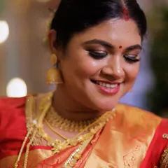 A classic South Indian reception look. This bride is wearing a beautiful Kanjivaram saree, and her makeup features a warm, glowing base with soft smokey eyes and a traditional low bun hairstyle.