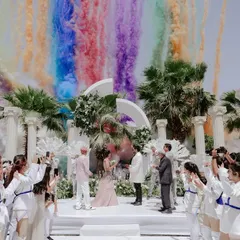A moment of pure, unadulterated joy. For this elegant white wedding, a burst of rainbow-colored smoke created a stunning, unexpected backdrop, proving that even the most serene celebrations can have a vibrant, playful heart.