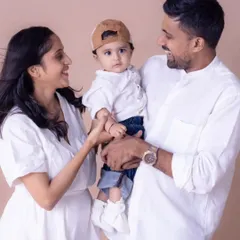 A candid and interactive family moment in the studio. The parents' focus is entirely on their little one, creating a natural and loving family portrait that feels unstaged and real.