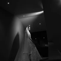 A dramatic black and white shot of a bride on a staircase, using a single light source to create a stunning, high-contrast image.