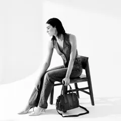 A minimalist black and white studio shot for Kompanero. This image focuses on the clean lines of the denim outfit and the classic design of the handbag, creating a timeless and elegant look.