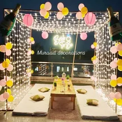 A fun and chic terrace setup for a "Bride to Be" party. The fairy light canopy creates a festive glow, while the low seating arrangement, paper lanterns, and champagne bottle balloons set the perfect mood for a bachelorette celebration.