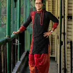 A full-length portrait showcasing the complete groom's outfit, including the dhoti. The setting on a vintage balcony adds to the traditional charm.