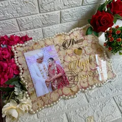 An angled view of the rectangular photo frame, showing the glossy finish and the heart-shaped cutout between the couple's names.